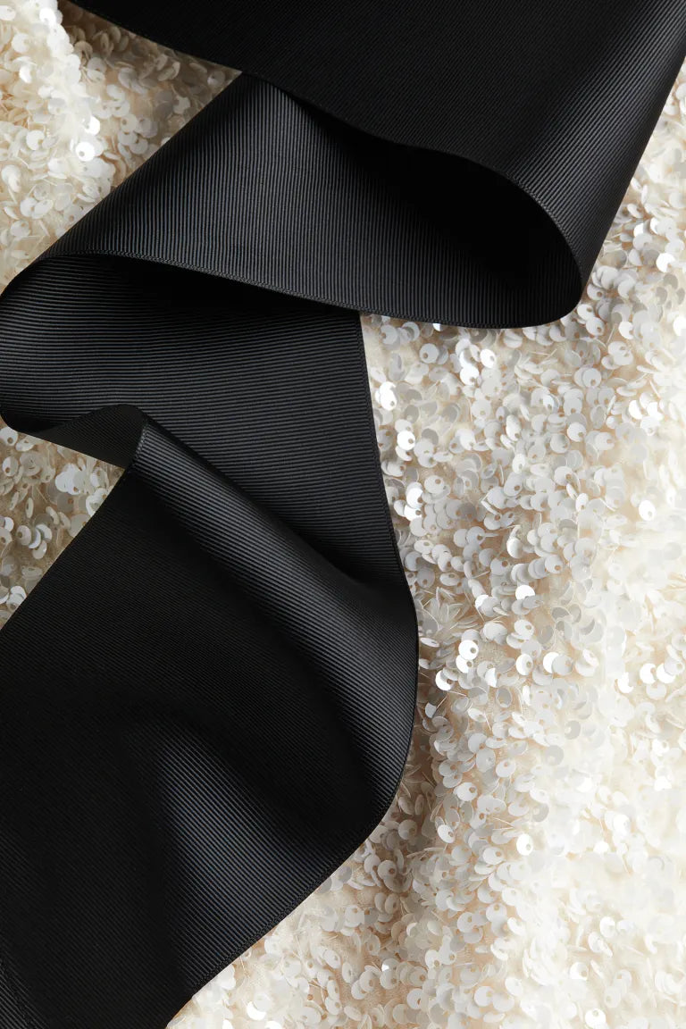 Melina | Elegant vit paljettklänning med svart rosett